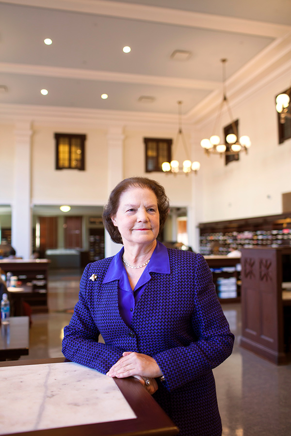 A posed portrait of Susan Cahoon in a blue dress suit with Emory's elegant Mattheson Reading Room in the background.