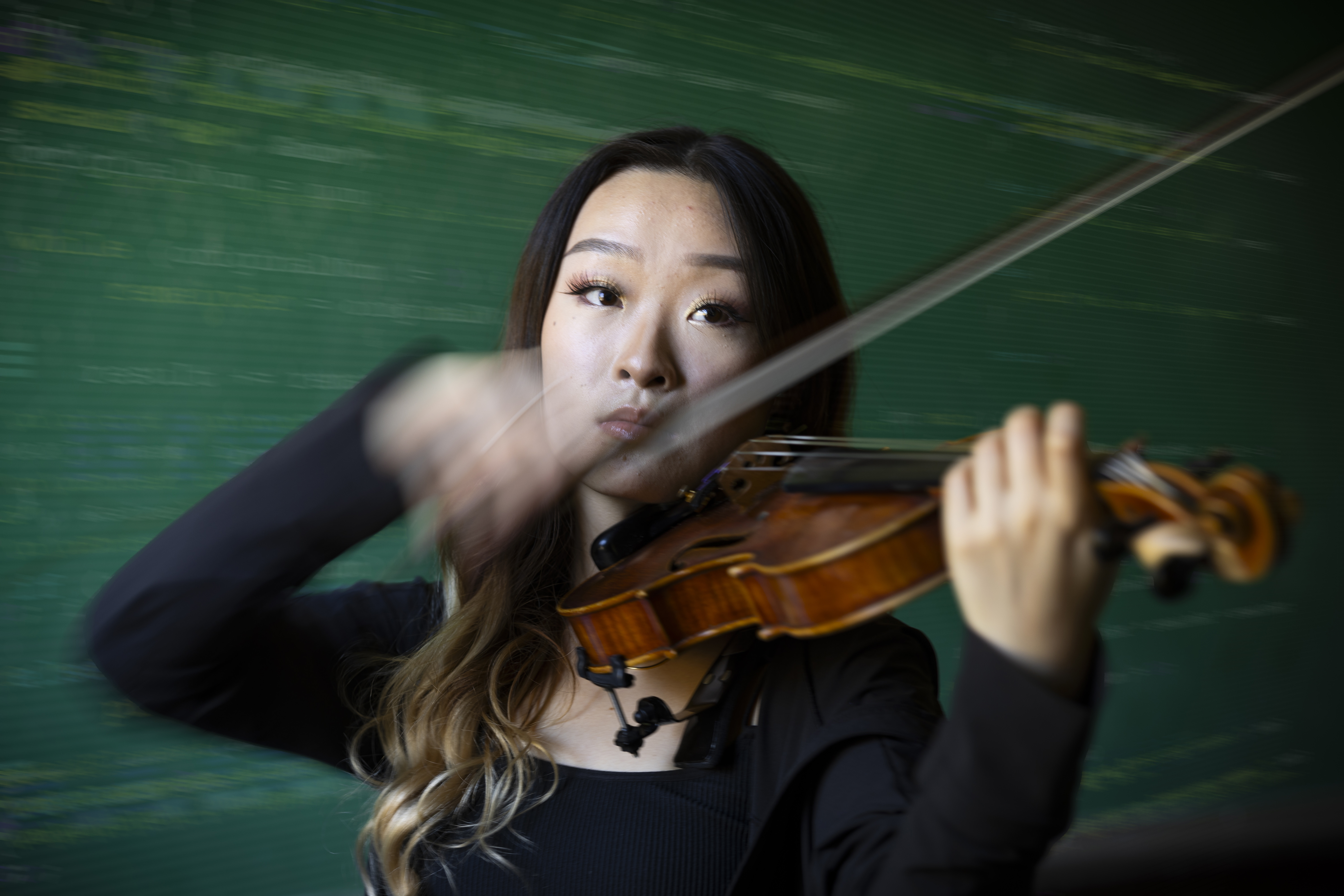 photo of student playing violin with coding in background