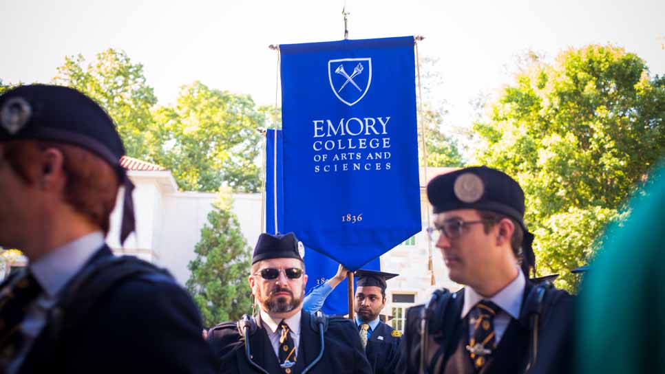 man walking with emory banner in procession