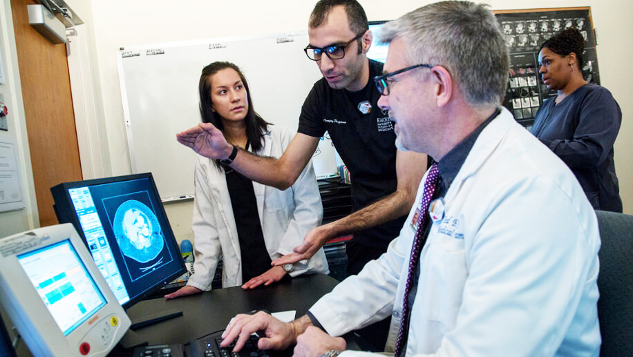 four medical professionals looking at an image on a screen
