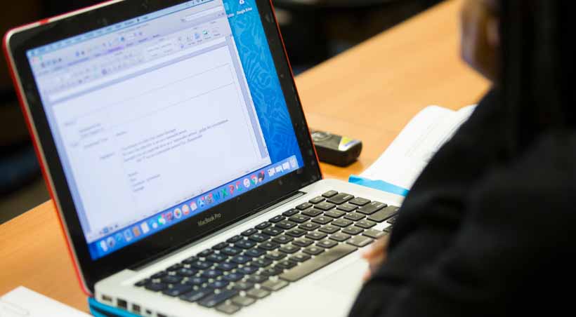 student reads document on laptop