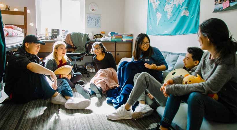 students sitting on floor of dorm room talking