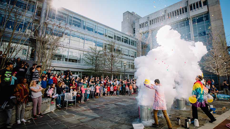 a crowd watches a fun explosion at the science festival