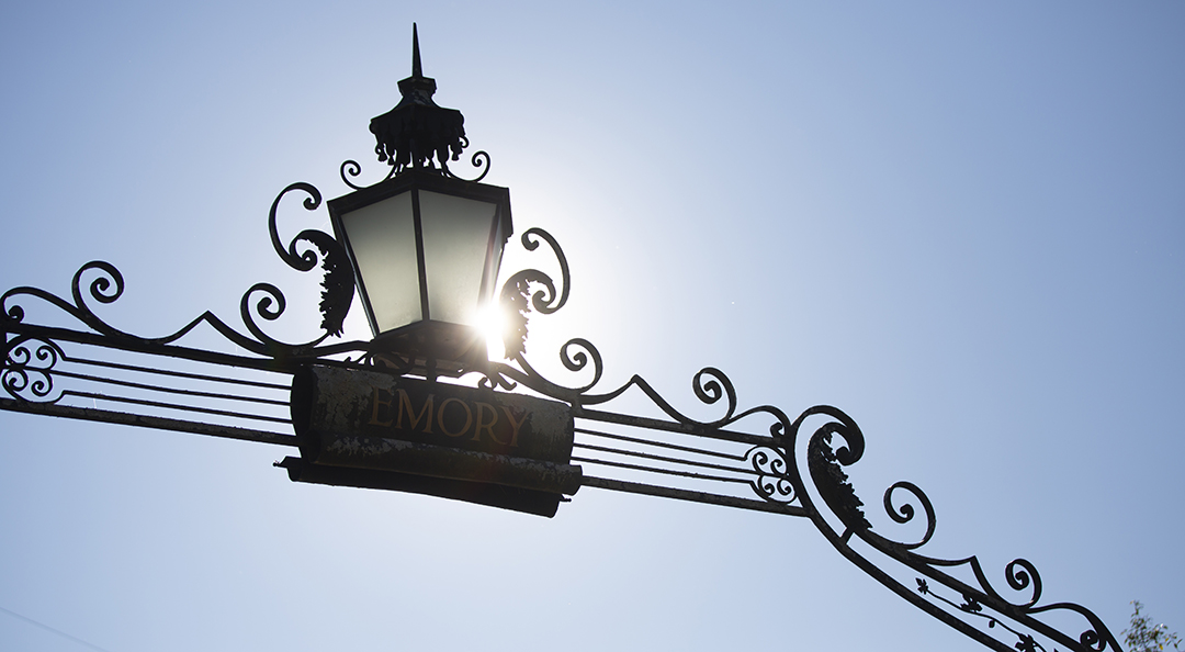 emory gate with blue sky and sunflare behind it